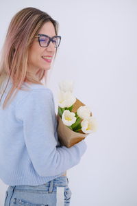 Portrait of young woman with flowers against white background