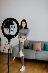 Portrait of young woman photographing with text on hardwood floor