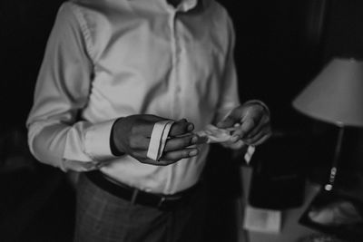 Midsection of man getting dressed while standing at home