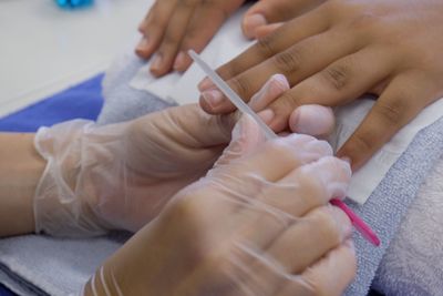 Cropped image of beautician cleaning woman fingernail