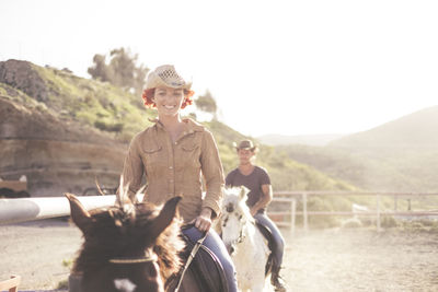 People riding horses on footpath against sky