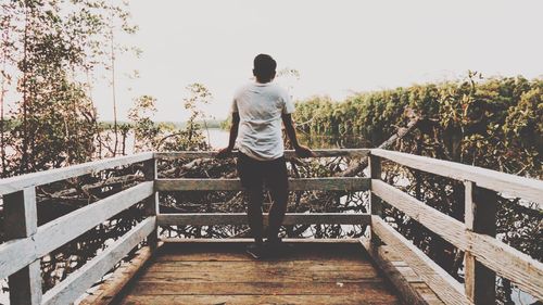 Rear view of man standing on footbridge