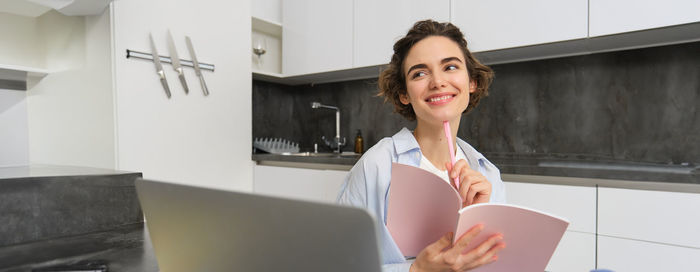 Portrait of young woman using mobile phone at home