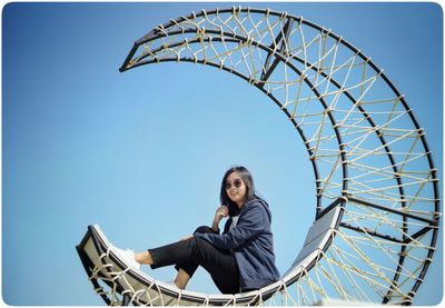 Low angle view of ferris wheel against clear blue sky