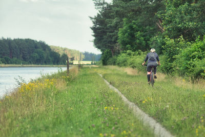 Rear view of man riding bycycle on field