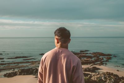 Rear view of man looking at sea against sky