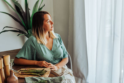 Woman sitting at the table in the kitchen preparing asparagus