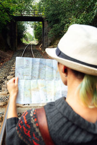 Rear view of man holding hat against trees