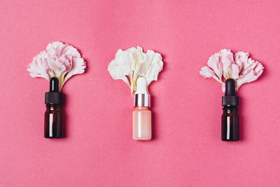 Serum in glass bottles with carnation petals. aromatherapy oil, natural cosmetics concept. minimal