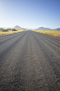 Road passing through landscape against clear sky