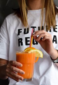 Midsection of woman holding orange juice