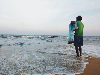 Rear view of woman standing on beach