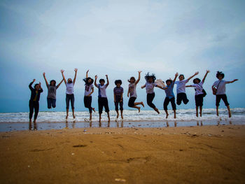 Group of people at beach against sky