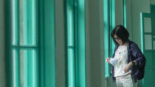 Side view of young woman standing against wall