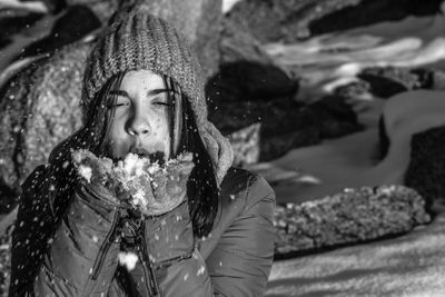 Portrait of teenage girl blowing snow on field