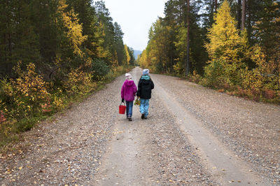 Rear view of people walking on road amidst trees