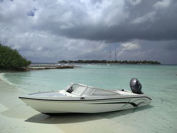 Boats in sea against cloudy sky