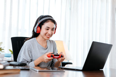 Smiling young woman playing video game at office