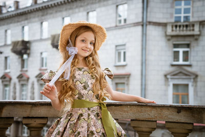 Little girl in dress and hat posing on the balcony