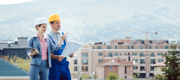 Woman standing with arms outstretched against buildings