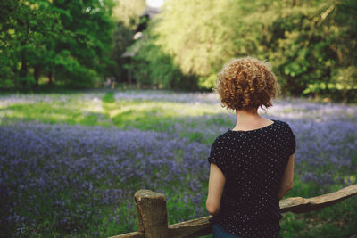 Rear view of woman standing against flowers at park