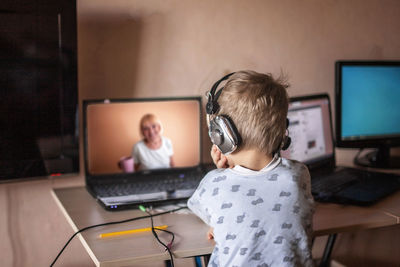 Cute boy talking with his grandmother within video chat on laptop, digital self-isolation
