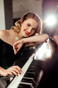 Close up of smiling teenage girl at home playing the piano