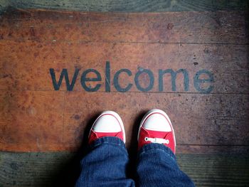 Low section of person standing in front of welcome sign on floorboard