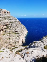 Rock formations by sea against blue sky