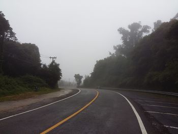 Road by trees against sky