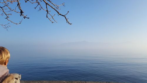 Tourist on lakeshore against clear sky