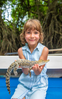 Portrait of young woman holding iguana
