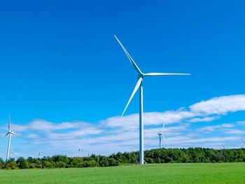 Windmill on field against blue sky