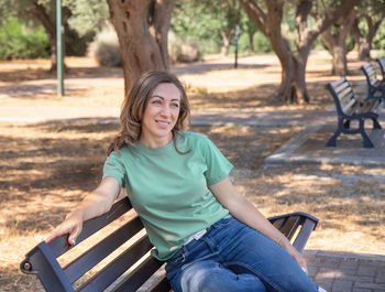 Portrait of smiling man sitting on bench in park