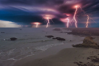 Firework display over sea against sky