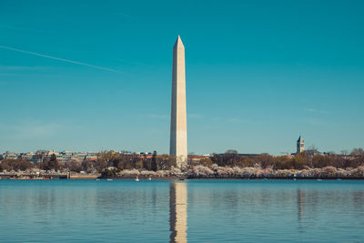 Washington monument by river against sky in city