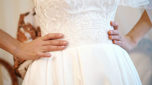 Midsection of bride holding wedding dress