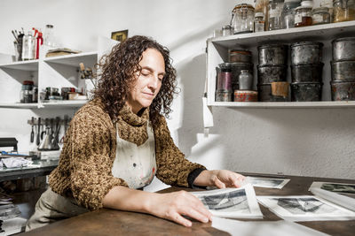 Female artist inspecting some pieces of hand made printings.