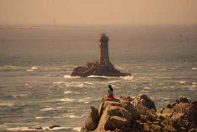 Lighthouse by sea against sky during sunset