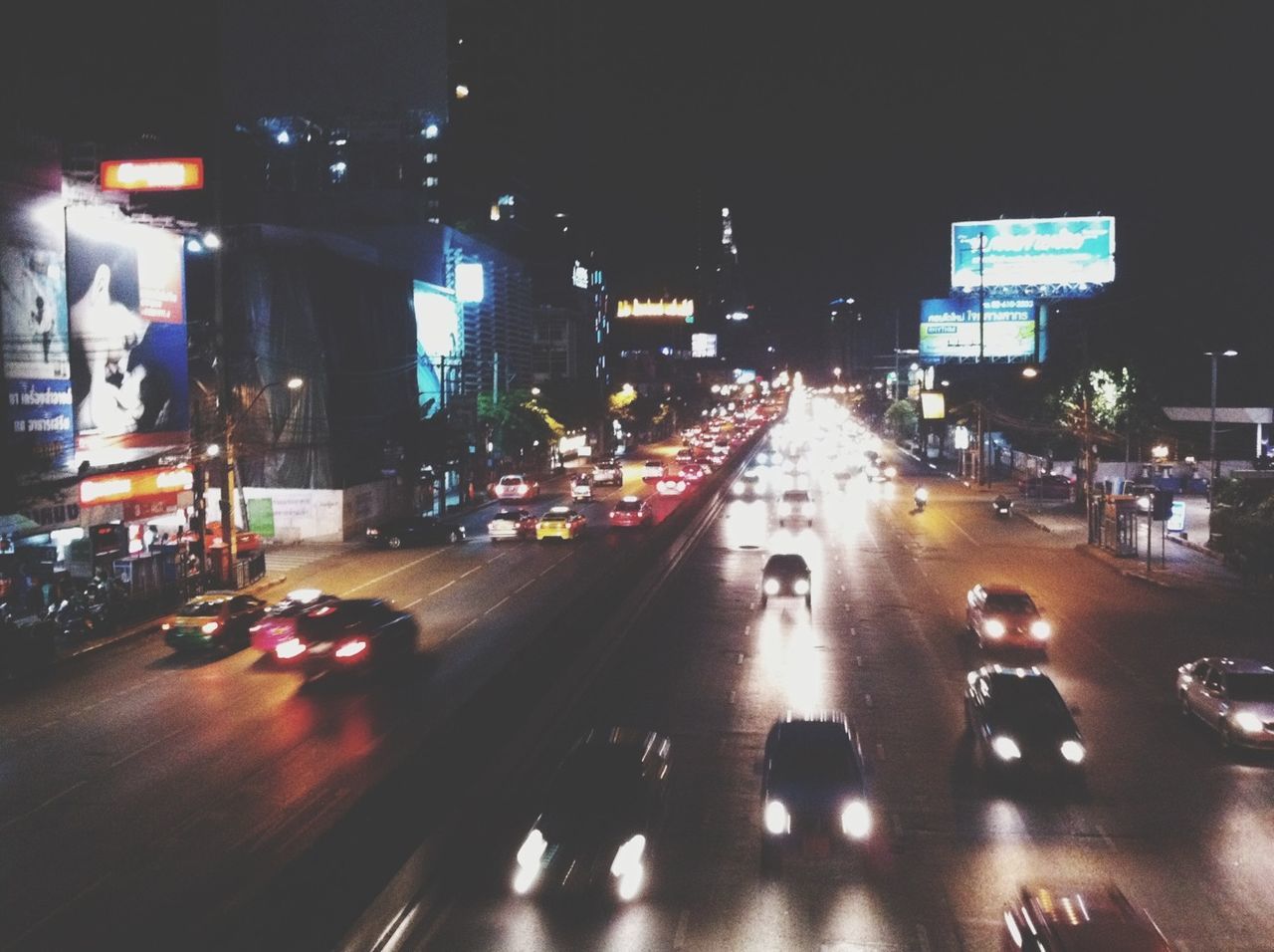 illuminated, night, city, transportation, building exterior, street, car, architecture, city street, city life, built structure, land vehicle, traffic, mode of transport, road, street light, on the move, high angle view, road marking, incidental people