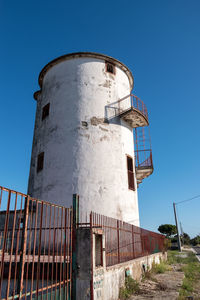 Low angle view of water tower against clear blue sky