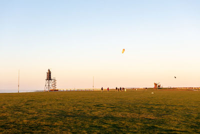Group of people on grassland against clear sky