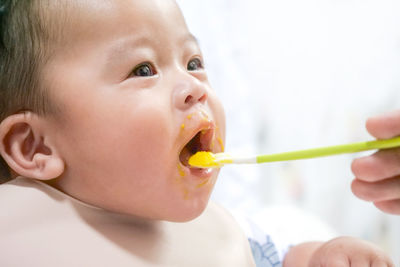 A happy asian baby boy sitting and feeding some pap pudding by mom with spoon.