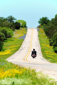 People riding motorcycle on road against sky