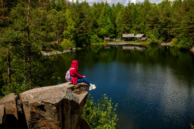 Rear view of man sitting on rock