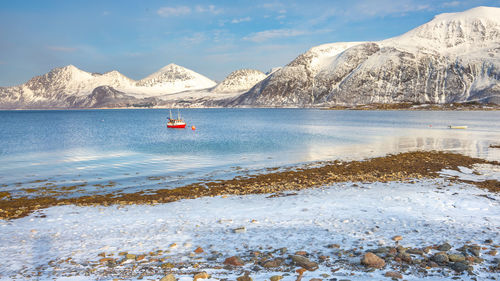 Scenic view of sea and snowcapped mountains against sky