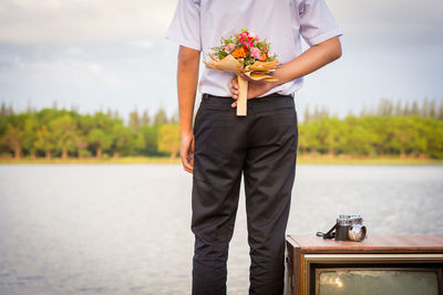 Woman holding flower standing by lake