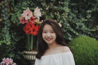 Portrait of smiling young woman standing against trees