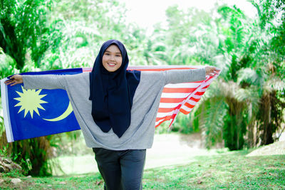 Muslim woman happy holding a malaysian flag. malaysia independence day.