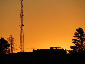 Low angle view of silhouette built structures against orange sky